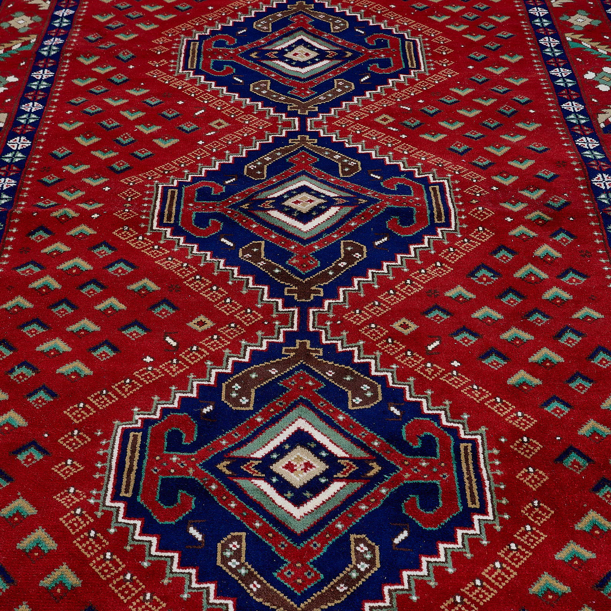 rug in deep red wool with triple diamond motif, demonstrating handwoven rug craftsmanship.