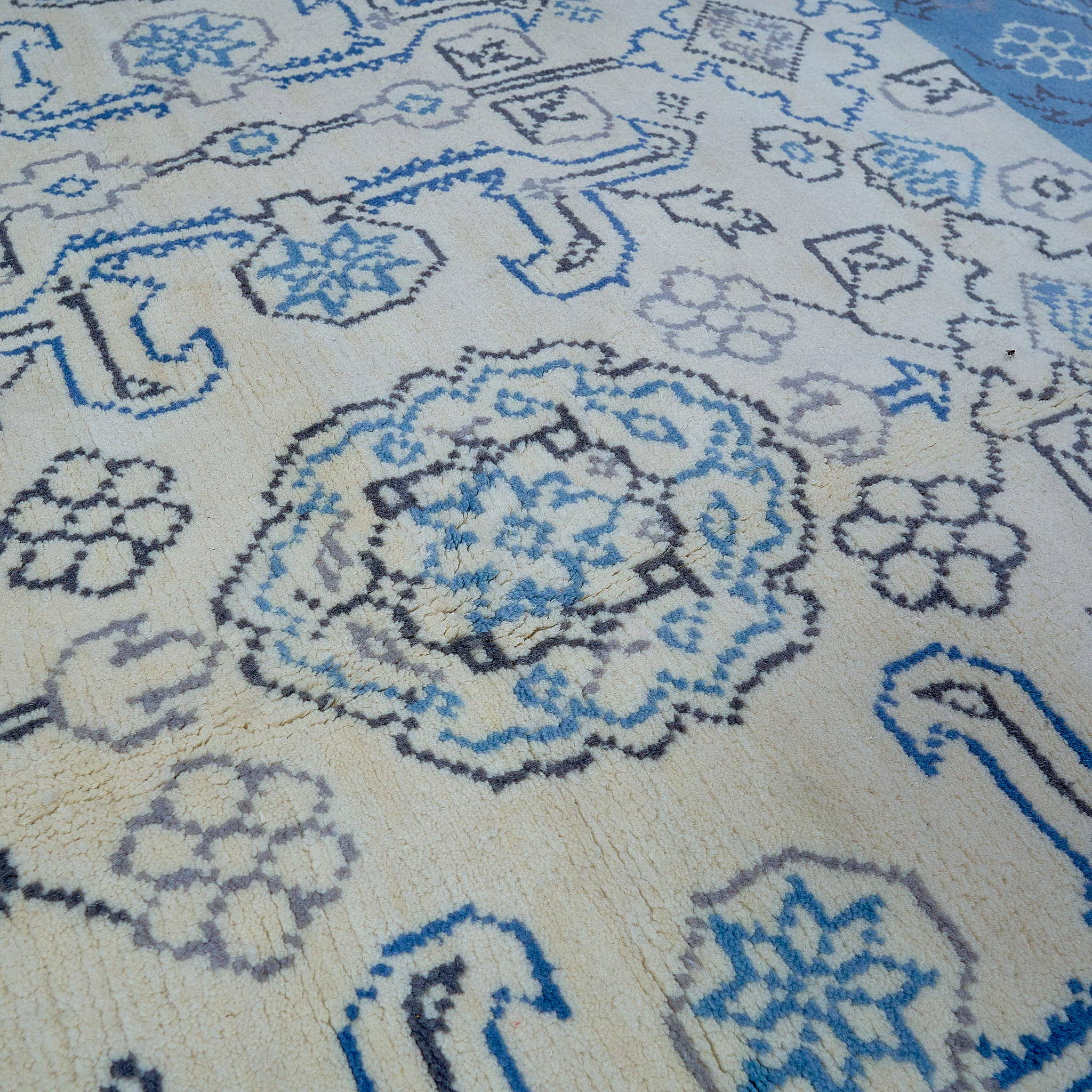 rug in beige wool with tilework/arabesque motif, demonstrating handwoven rug craftsmanship.