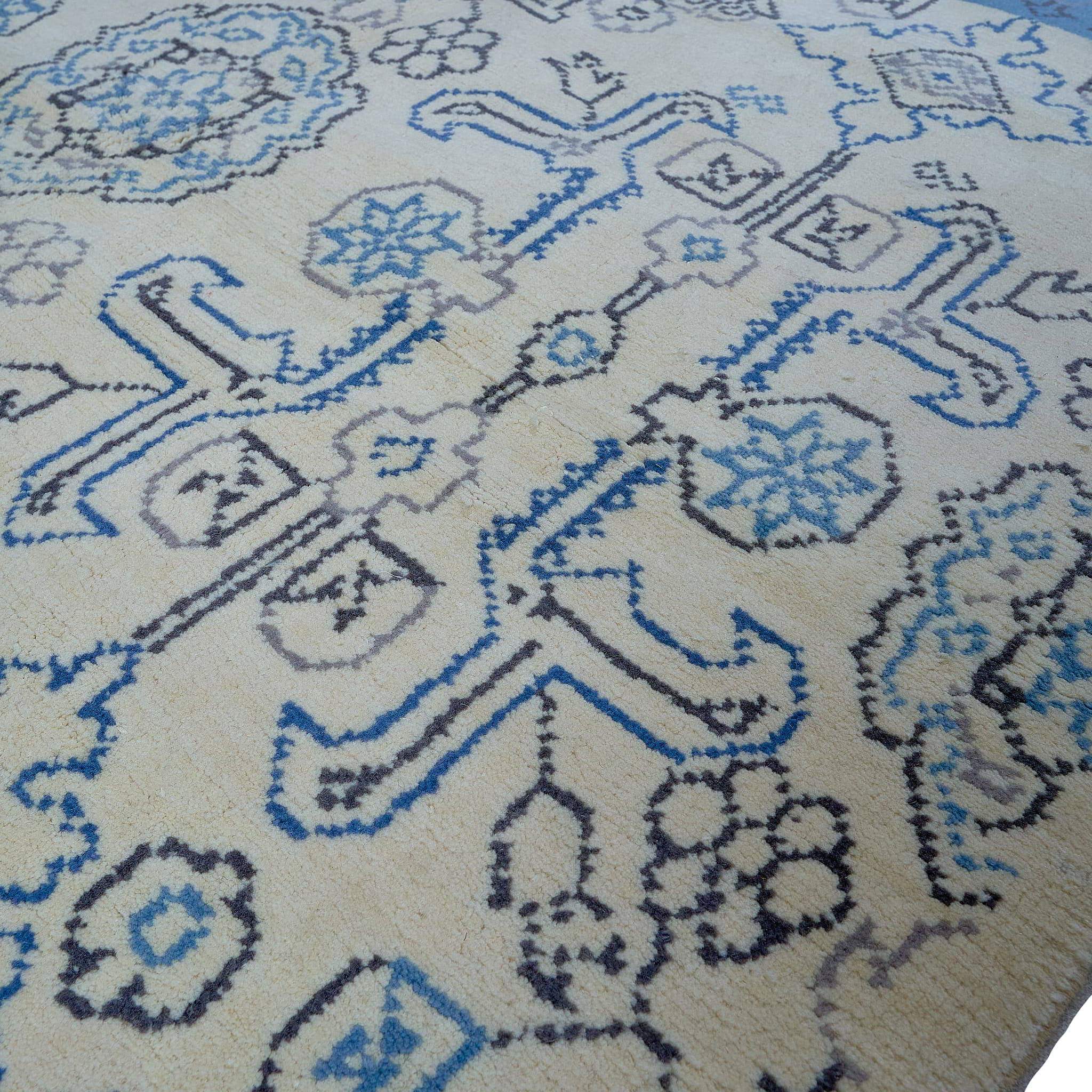 rug in beige wool with tilework/arabesque motif, demonstrating handwoven rug craftsmanship.