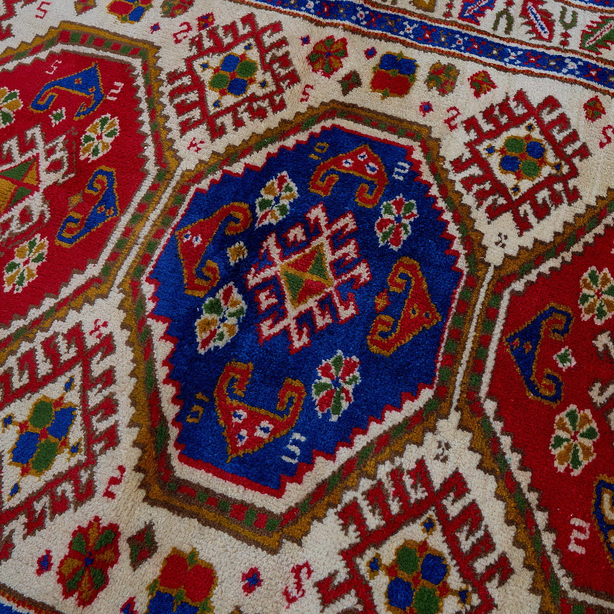 rug in deep red wool with triple medallion motif, demonstrating handwoven rug craftsmanship.