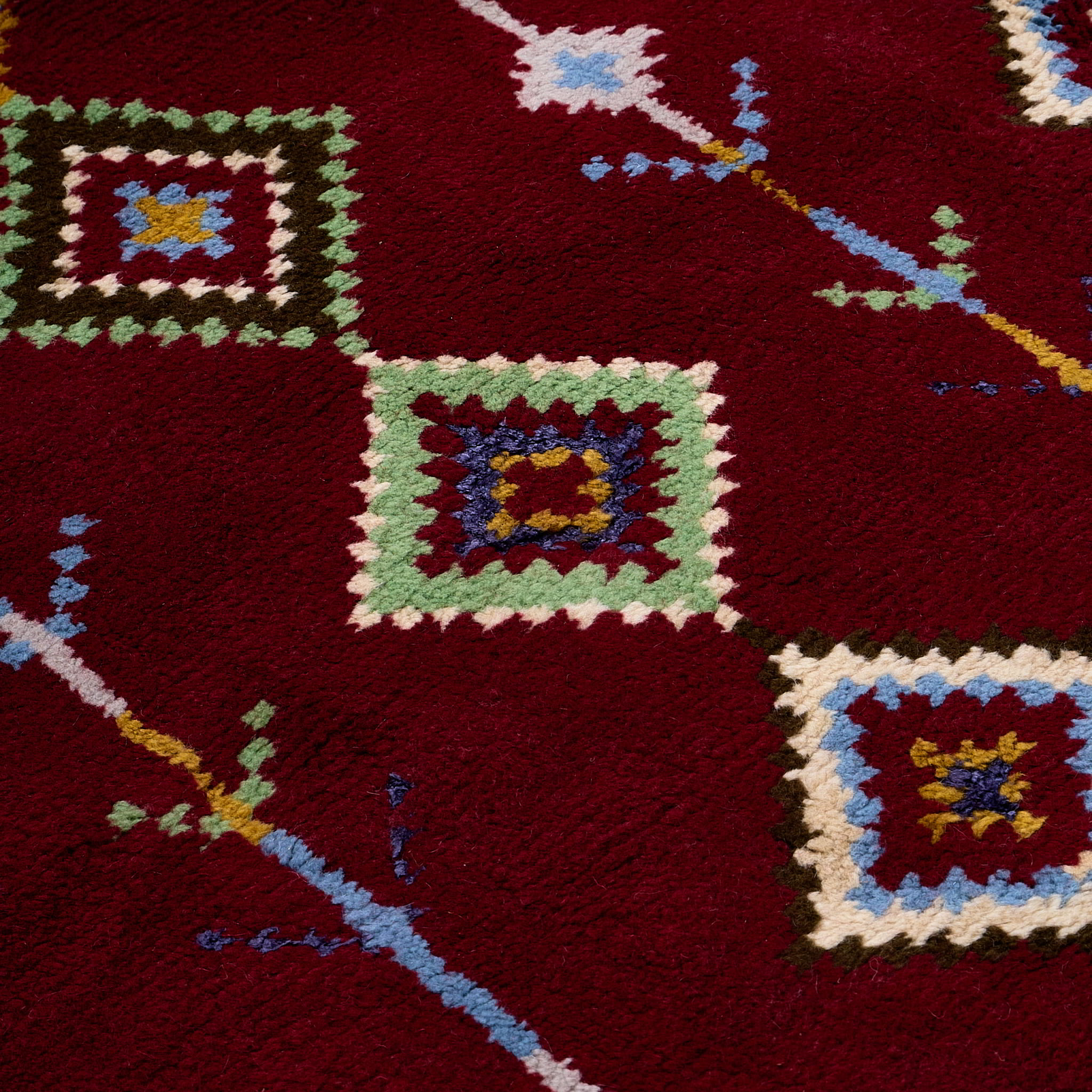 rug in deep red wool with diamond pathway motif, demonstrating handwoven rug craftsmanship.