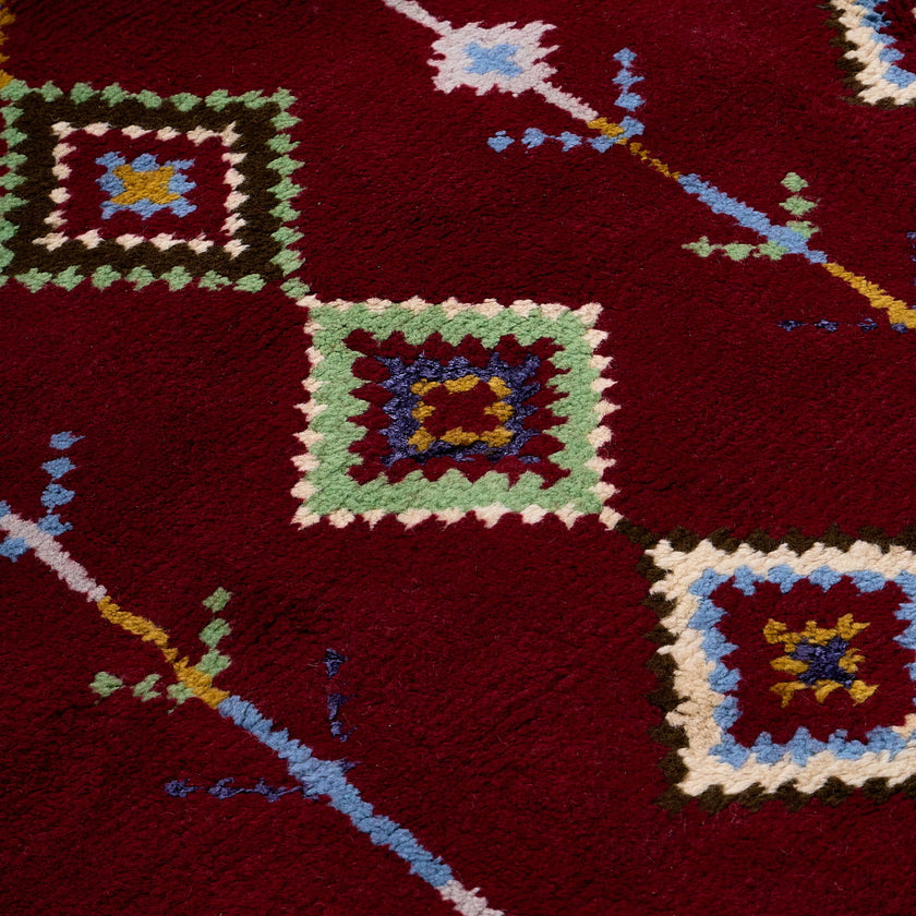 rug in deep red wool with diamond pathway motif, demonstrating handwoven rug craftsmanship.