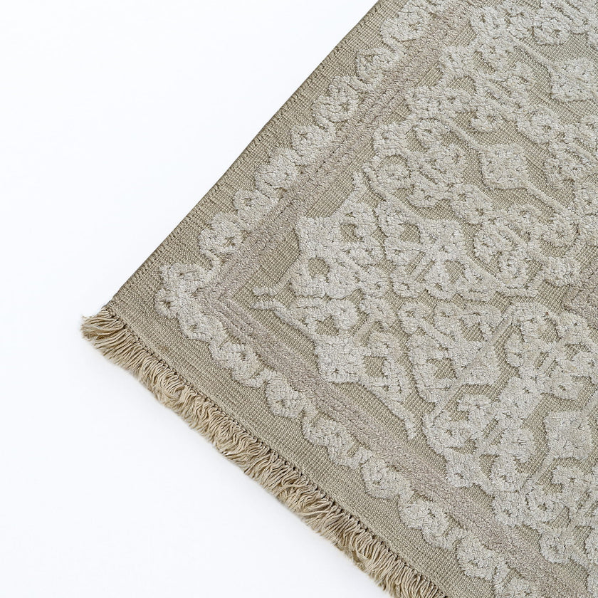 rug in beige cotton-silk blend with quiet floral field motif, demonstrating handwoven rug craftsmanship.