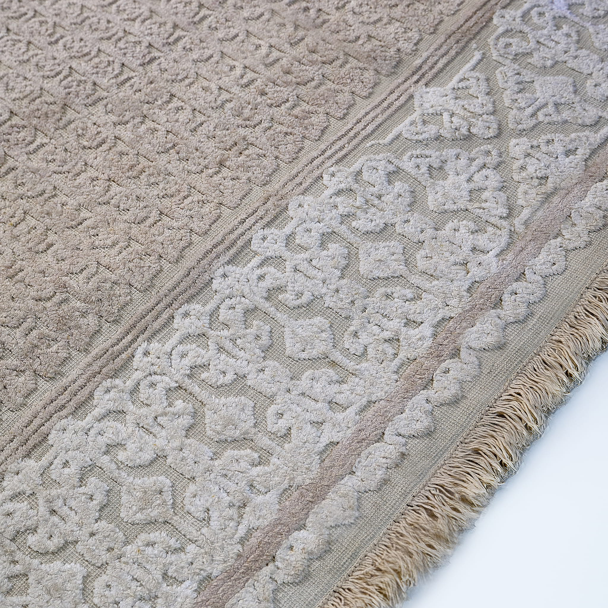 rug in beige cotton-silk blend with quiet floral field motif, demonstrating handwoven rug craftsmanship.