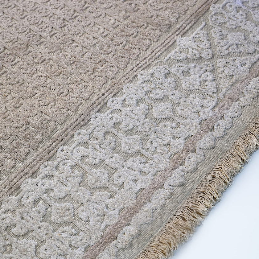 rug in beige cotton-silk blend with quiet floral field motif, demonstrating handwoven rug craftsmanship.