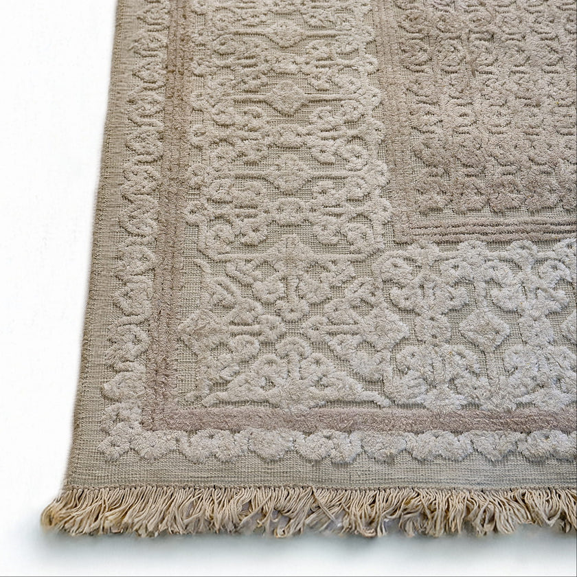 rug in beige cotton-silk blend with quiet floral field motif, demonstrating handwoven rug craftsmanship.