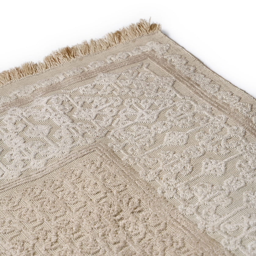rug in beige cotton-silk blend with quiet floral field motif, demonstrating handwoven rug craftsmanship.