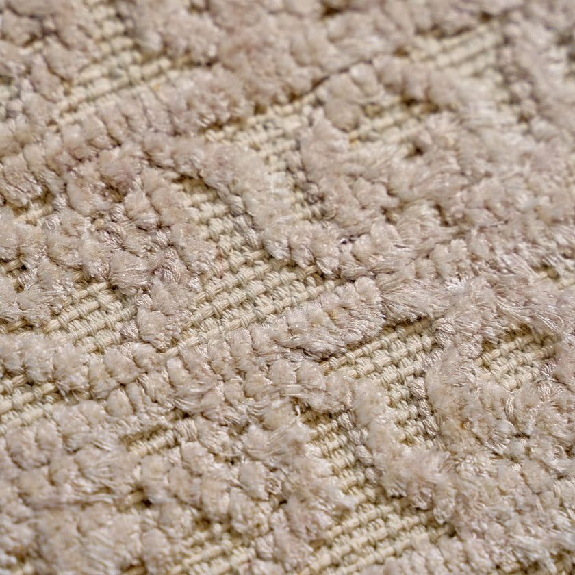 rug in beige cotton-silk blend with quiet floral field motif, demonstrating handwoven rug craftsmanship.
