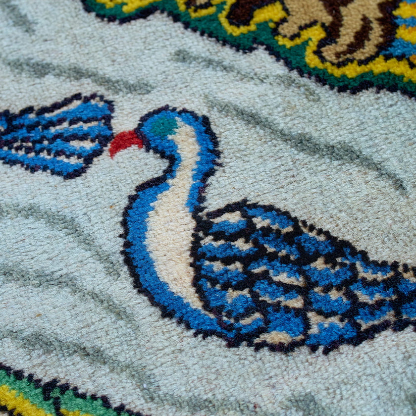 wall art in green wool with figurative village textile motif, demonstrating handwoven rug craftsmanship.